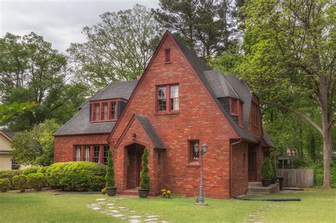 red brick house with brown metal roof|black shingles on brick house.